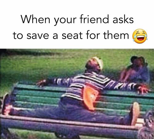 a man laying on top of a green park bench next to another person sitting down