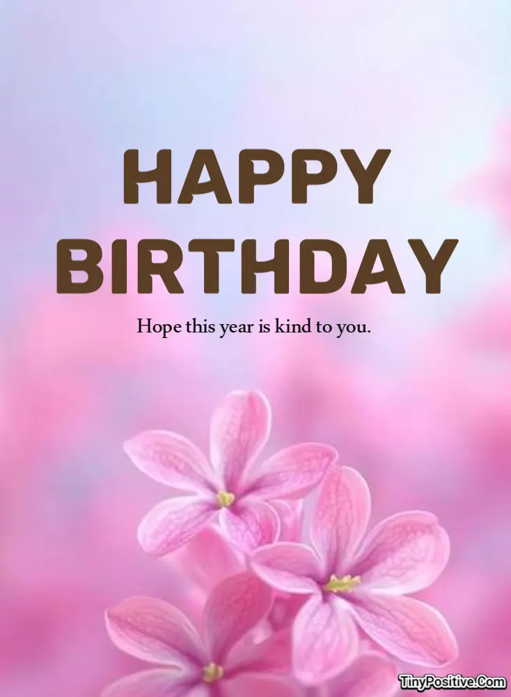 A floral birthday card reading 'HAPPY BIRTHDAY Hope this year is kind to you.' set against a soft purple and pink background with blooming lavender-pink flowers.